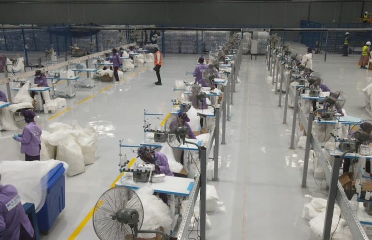 Workers at sewing stations on the floor of a mosquito net factory